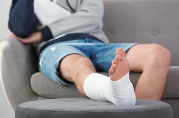 A photo of man sitting on a couch with personal injury on his right leg.