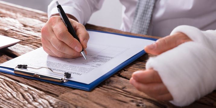 A photo of a person with a personal injury in right hand, signing a paper.
