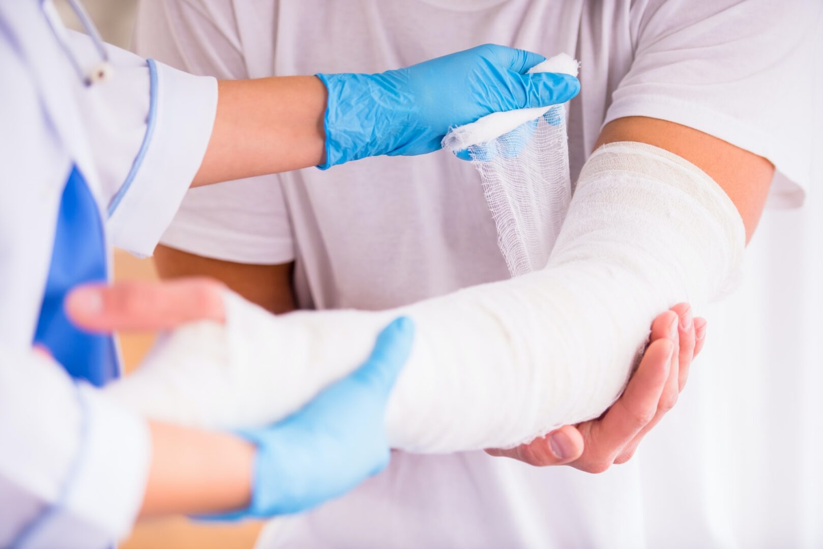 A doctor is treating a personal injury by applying a bandage to a patient's arm.