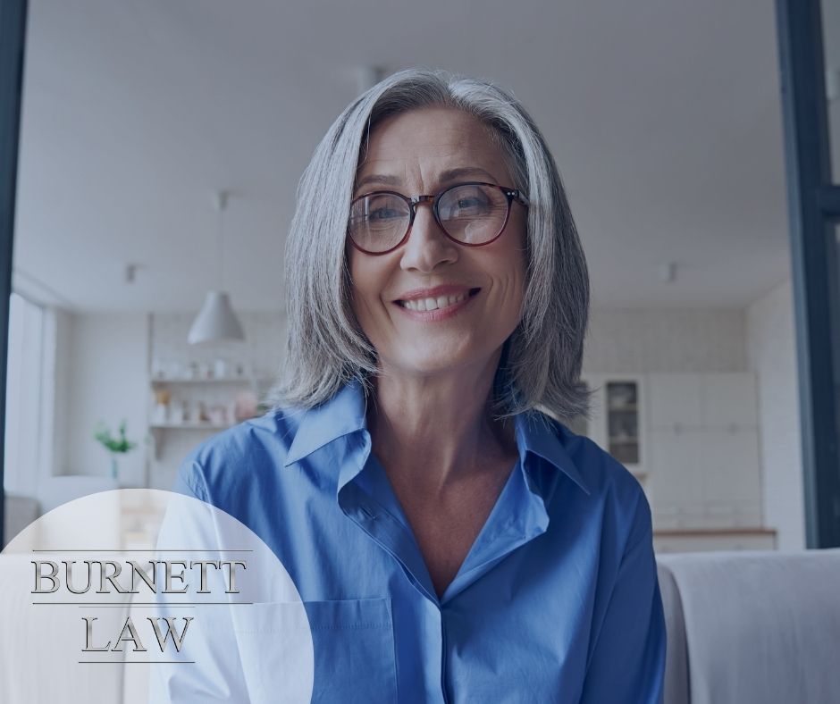 A woman in glasses sitting in a living room with the words burnette law.